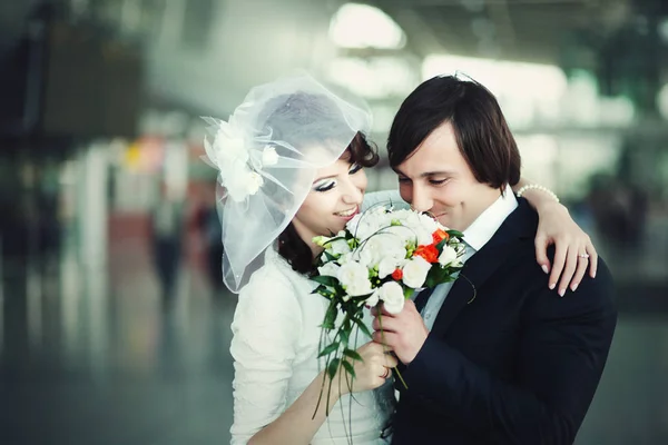 Pareja de boda sonríe mientras huele un ramo de boda —  Fotos de Stock