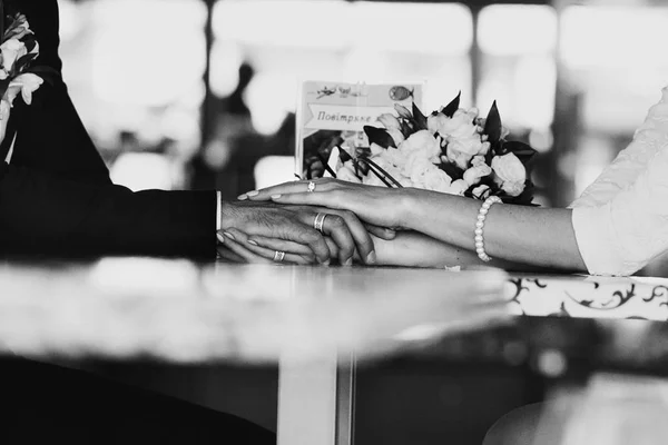 Black and white picture of newlyweds hands lying on the cafe tab — Stock fotografie