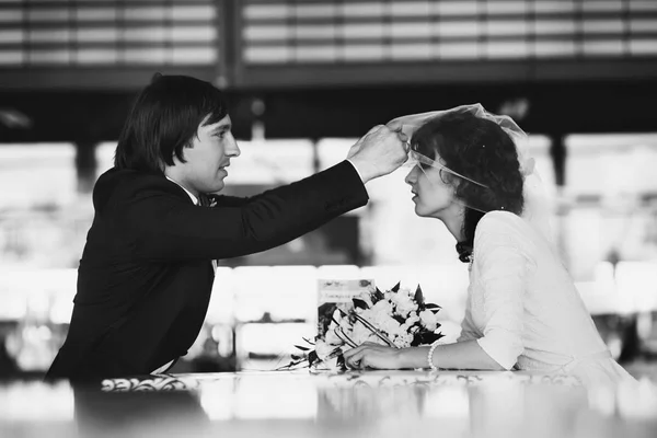 Groom levanta o véu da noiva enquanto eles se sentam no café — Fotografia de Stock