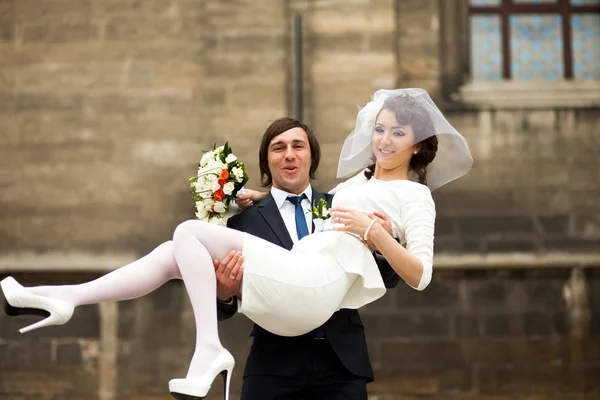 Happy groom hold in his hands a stylish bride in short dress — Stock Photo, Image