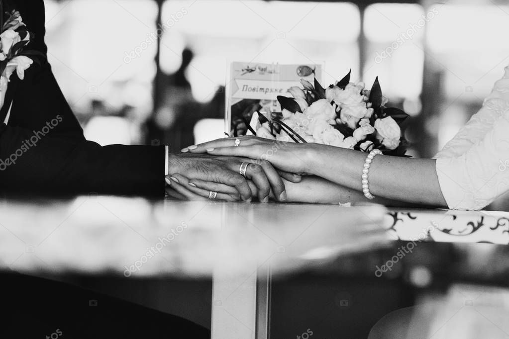 Black and white picture of newlyweds hands lying on the cafe tab