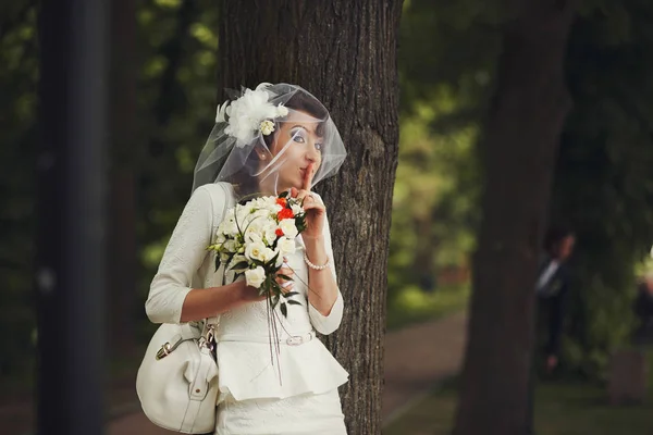 Rövid ruhát menyasszony tart ujjának mögött rejtőzik beh ajka — Stock Fotó