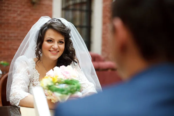 外のテーブルに座っている新郎をブルネット花嫁の笑顔します。 — ストック写真