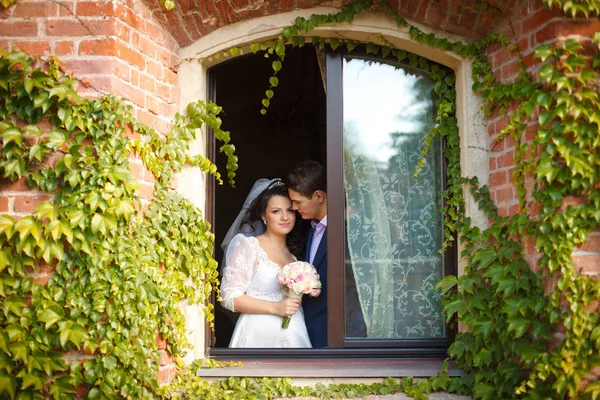 Superbe couple de mariage se tient dans la fenêtre d'un vieux hou brich — Photo