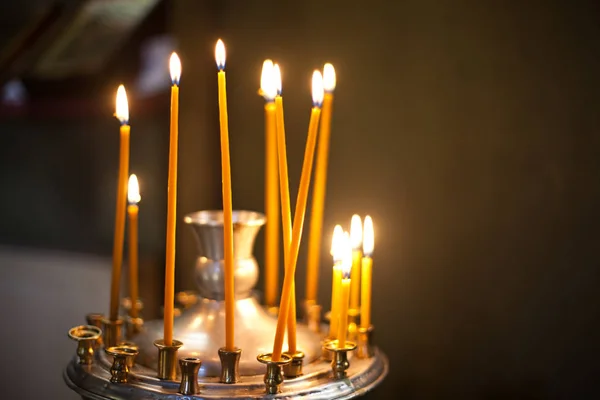 Високі жовті свічки стоять на сталевому свічнику в церкві — стокове фото