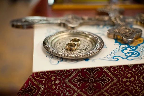 Оригінальні обручки лежать на сталевій тарілці на столі в церкві — стокове фото