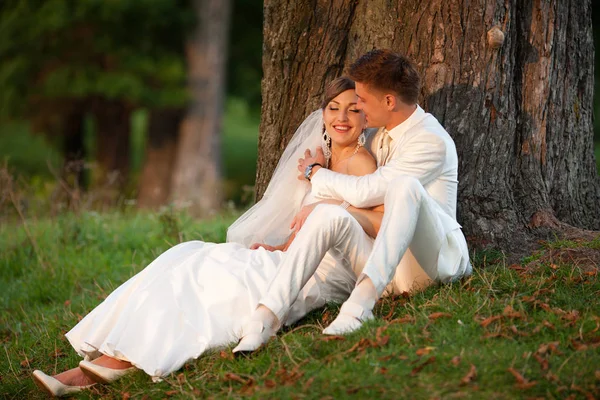 Groom hugs a bride from behind while she lies on his knees — Stock Photo, Image