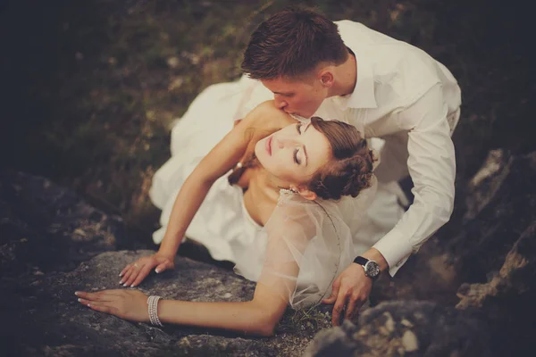 Жених целует невесту, лежащую на камнях — стоковое фото