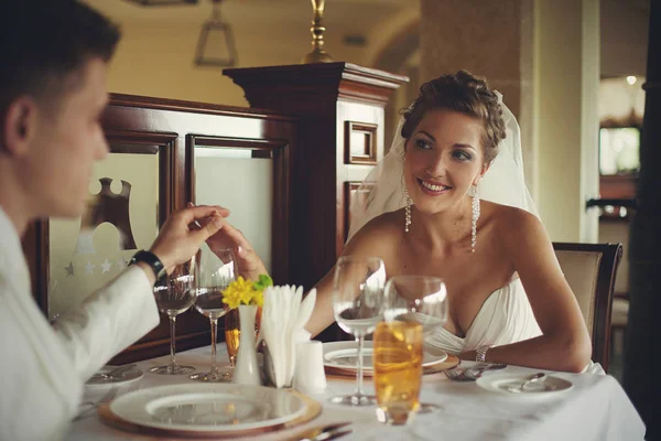 Superbe mariée tient la main du marié assis dans le restaurant — Photo