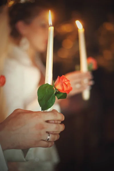 Les jeunes mariés tiennent des bougies blanches avec des roses rouges dans leurs mains — Photo