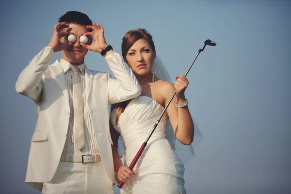 Groom tient des balles de golf devant ses yeux tandis que la mariée tient — Photo