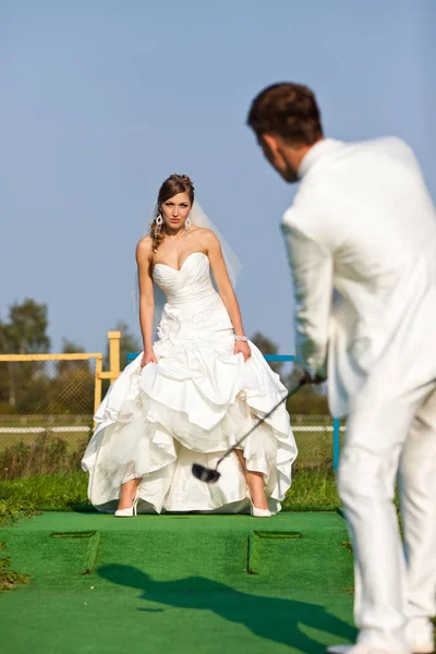 Vőlegény tolja a labdát, a golf ösvényen a menyasszony — Stock Fotó