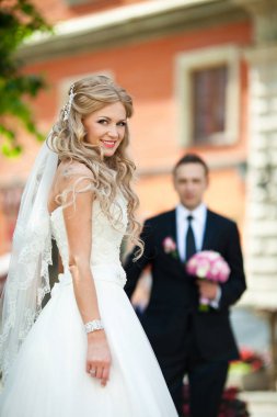 Muhteşem sarışın kıvırcık çarpıcı gelinle önünde duruyor