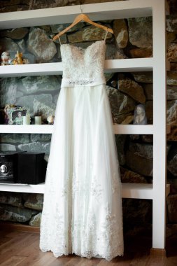 Beyaz elbise raflardan tuğla duvarda asılı.