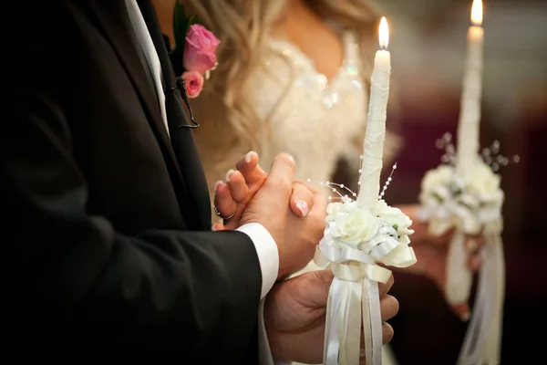 Groom segura a mão da noiva atrás de uma vela durante a cerimônia em — Fotografia de Stock