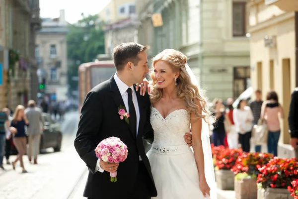 Glückliches Hochzeitspaar posiert auf der blühenden alten Straße — Stockfoto