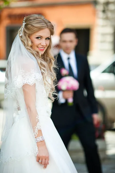 Χαμογελαστός νύφη φαίνεται πάνω από τους ώμους της ενώ γαμπρός περιμένει την — Φωτογραφία Αρχείου