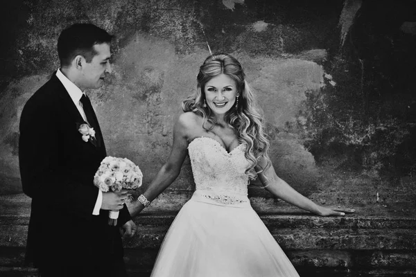 Черно-белая фотография потрясающей невесты, опирающейся на старую стену — стоковое фото