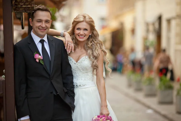 Sposo si appoggia ad un portico in legno in piedi con una sposa — Foto Stock