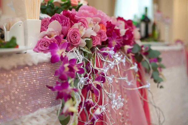 Guirlande de fleurs roses pend de la table à manger décorée avec p — Photo