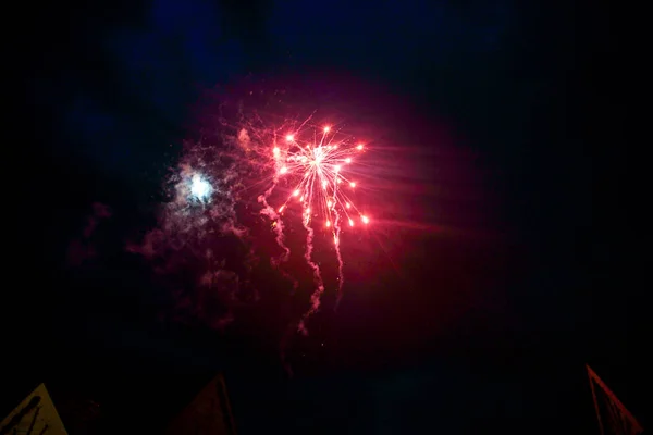 Красный фейерверк сияет над зданием в ночном небе — стоковое фото