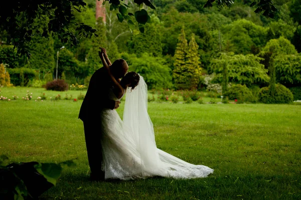 Image sombre d'un marié embrassant une mariée sur la pelouse — Photo