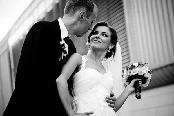 Der Bräutigam blickt der Braut in die Augen, die vor einem Stahlbui steht — Stockfoto