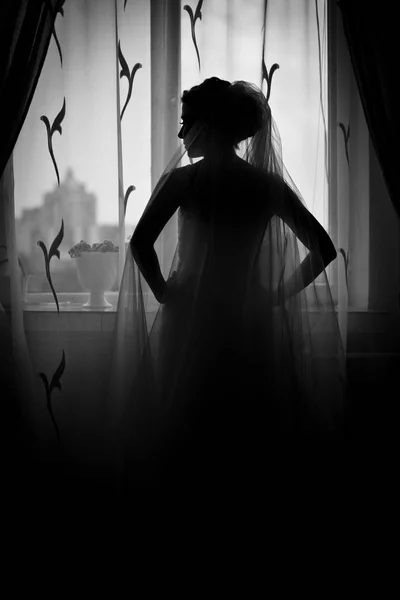 Thoughtful bride stands in the front of a window — Stock Photo, Image