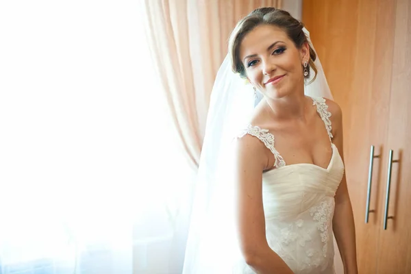 Pretty thin bride looks over her shoulder standing behind a wind — Stock Photo, Image