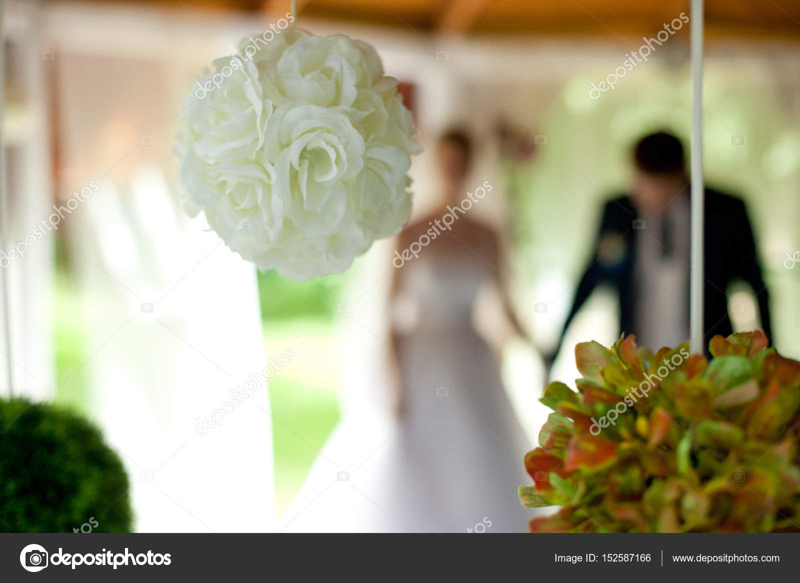 Rose Balls Hang From Ceiling While Newlyweds Stand On The