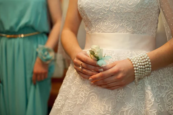 Noiva segura em sua mão um boutonniere decorado com penas de hortelã — Fotografia de Stock