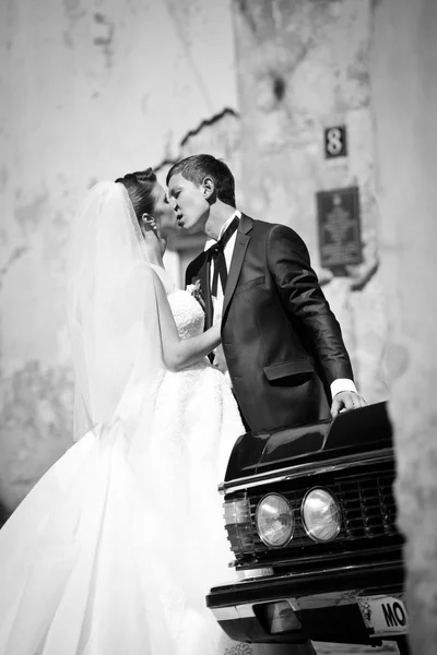 Fekete-fehér kép az esküvő pár, hogy az autó hajlik — Stock Fotó