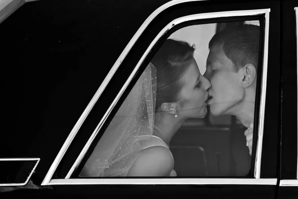 Black and white picture of wedding couple kissing in the limousi — Stock Photo, Image