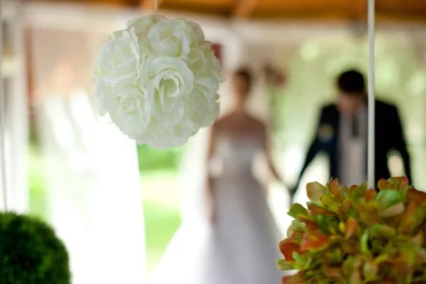 Rose balls hang from ceiling while newlyweds stand on the backgr