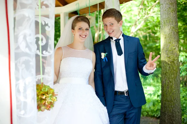 Laughing bride and groom stand on a white porch — Stock Photo, Image