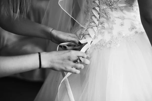 Un primo piano delle mani della signora che allacciano il corsetto della sposa — Foto Stock