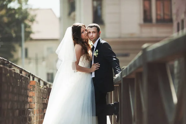 Sposo si appoggia su un ponte in piedi dietro una sposa — Foto Stock