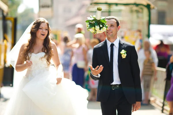 Groom lance un bouquet tout en marchant avec une mariée — Photo