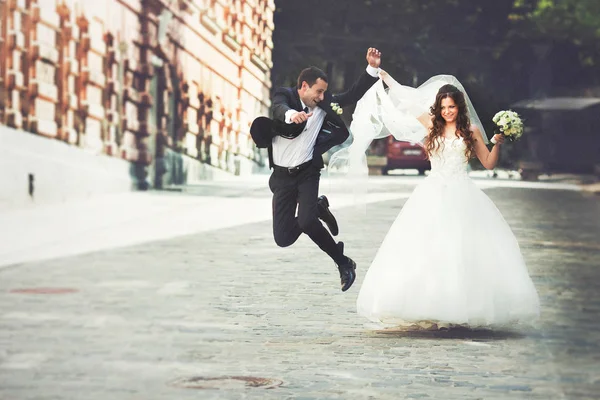 Feliz novio salta caminando por la calle con una novia — Foto de Stock