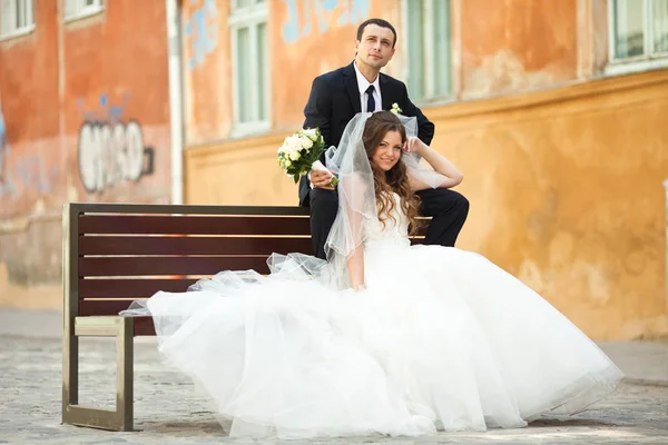 Groom parece sonhador sentado no banco atrás de uma noiva — Fotografia de Stock