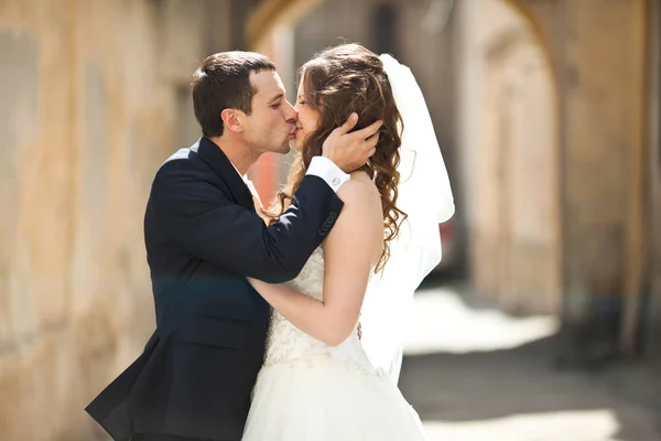 Novio sostiene la cabeza de la novia besándola en el callejón — Foto de Stock