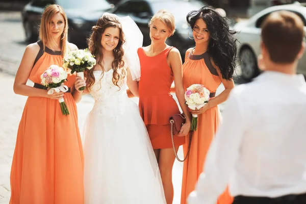 Novia rizada posa con damas de honor bonitas en vestidos de naranja — Foto de Stock