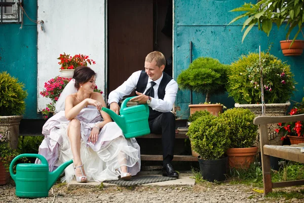Groom tient un grand pot d'arrosage devant une mariée — Photo