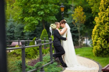 Uzun duvak gelin çelik çit yaslanmış bir damat hugs 