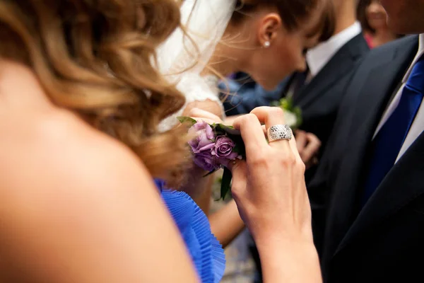 Mulher de vestido azul segura um boutonniere violeta em suas mãos — Fotografia de Stock