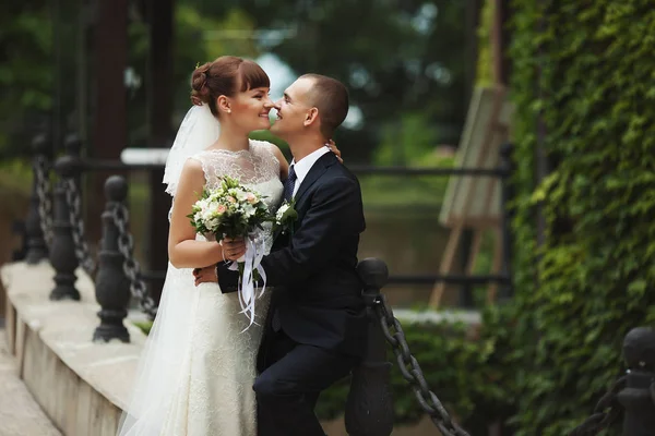 Feliz recém-casados posar inclinado sobre a cadeia enorme — Fotografia de Stock