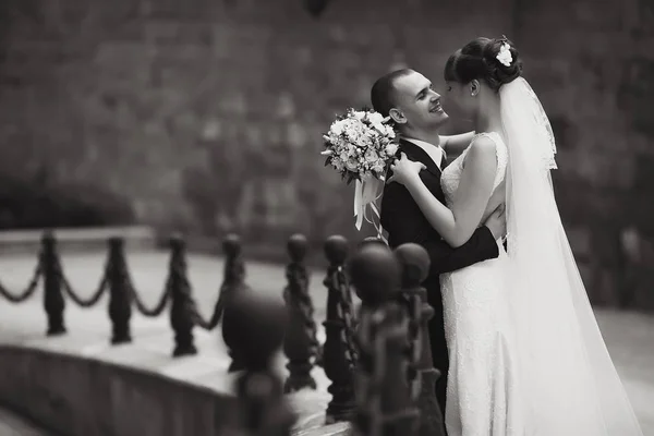 Bräutigam blickt der Braut in die Augen und hält sie zärtlich auf der Brücke — Stockfoto