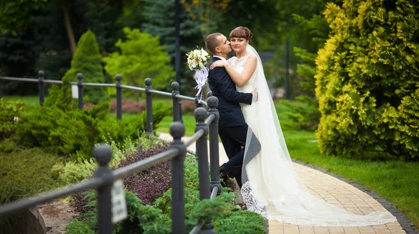 Lungo velo sposa si trova sul sentiero mentre lei sta con uno sposo — Foto Stock