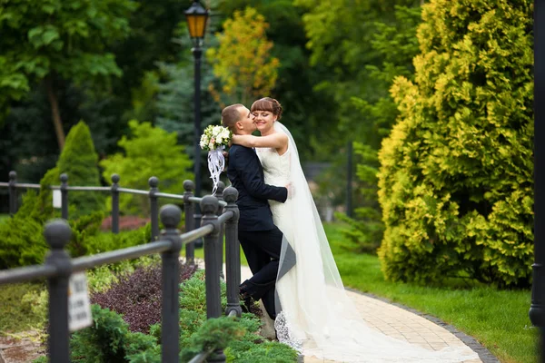 Groom segura noiva macia escondida sob o véu — Fotografia de Stock