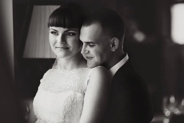 Le marié souriant se penche sur l'épaule de la mariée en l'embrassant par derrière — Photo